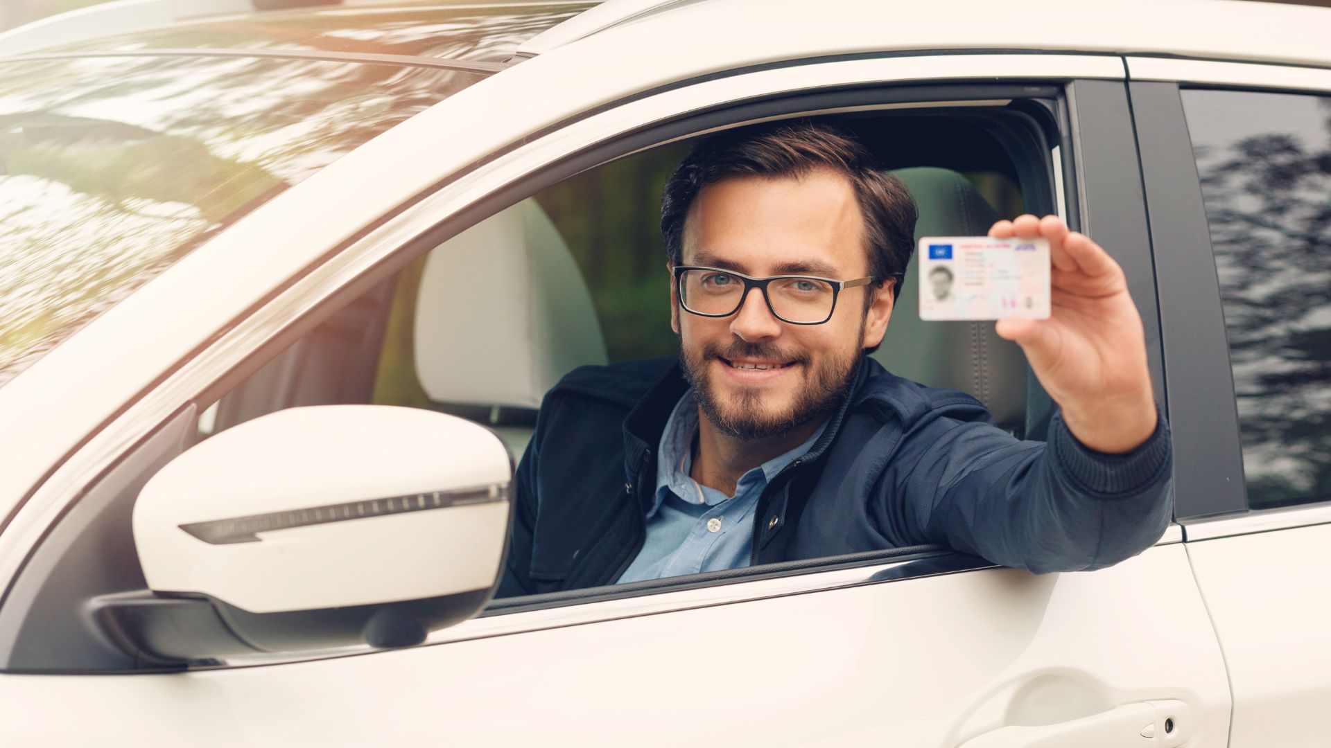 Man showing drivers license from car window.