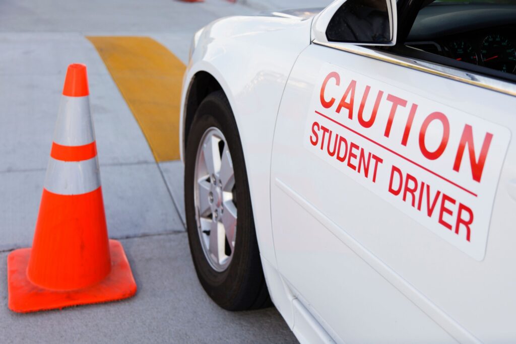 Student driver car with caution sign and traffic cone.