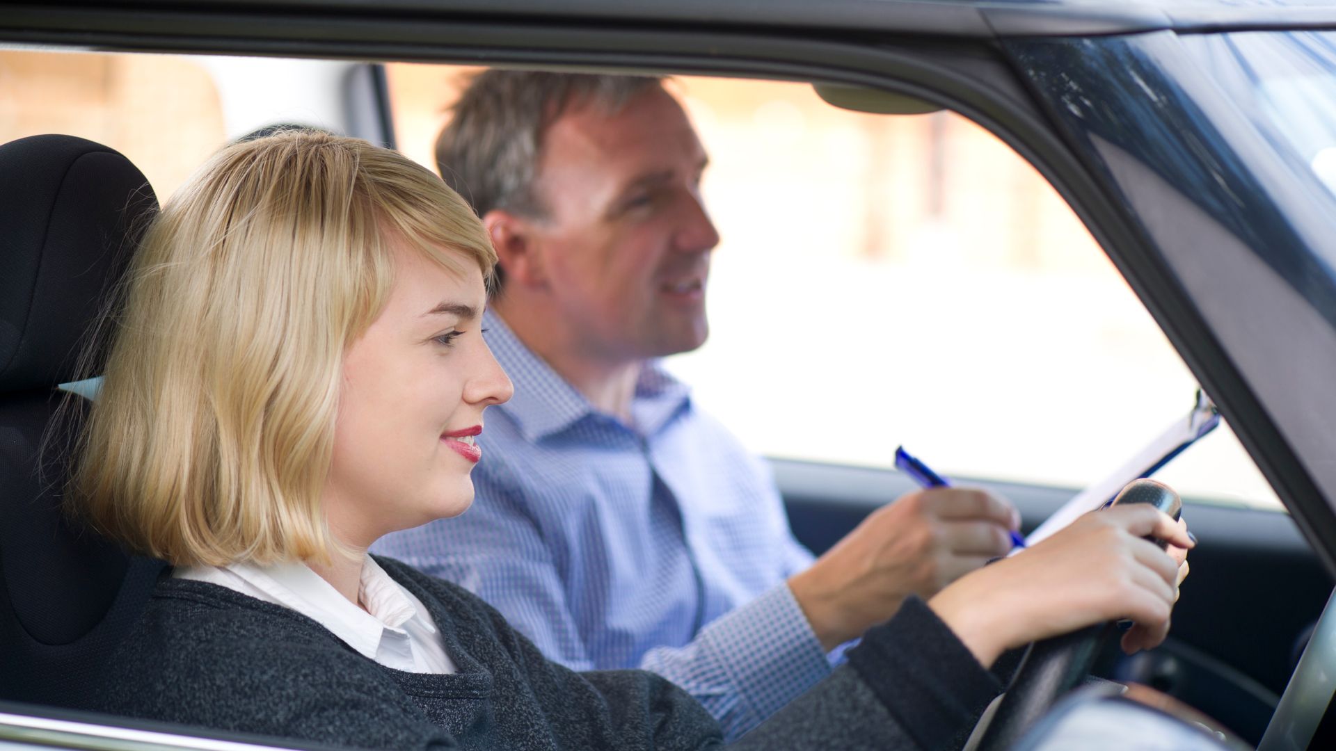 Woman learning to drive with instructor in car.