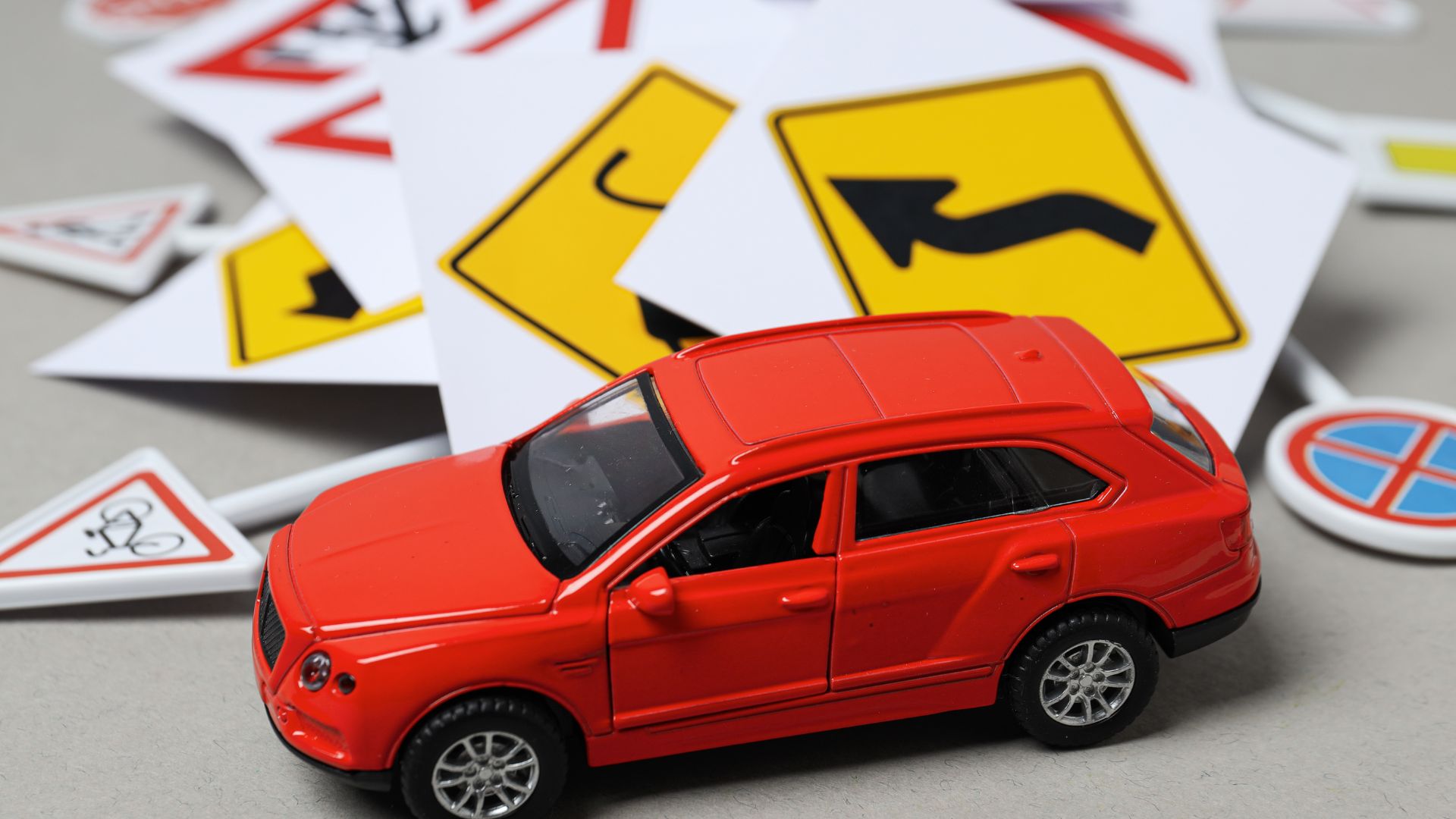 Red toy car among scattered road signs.