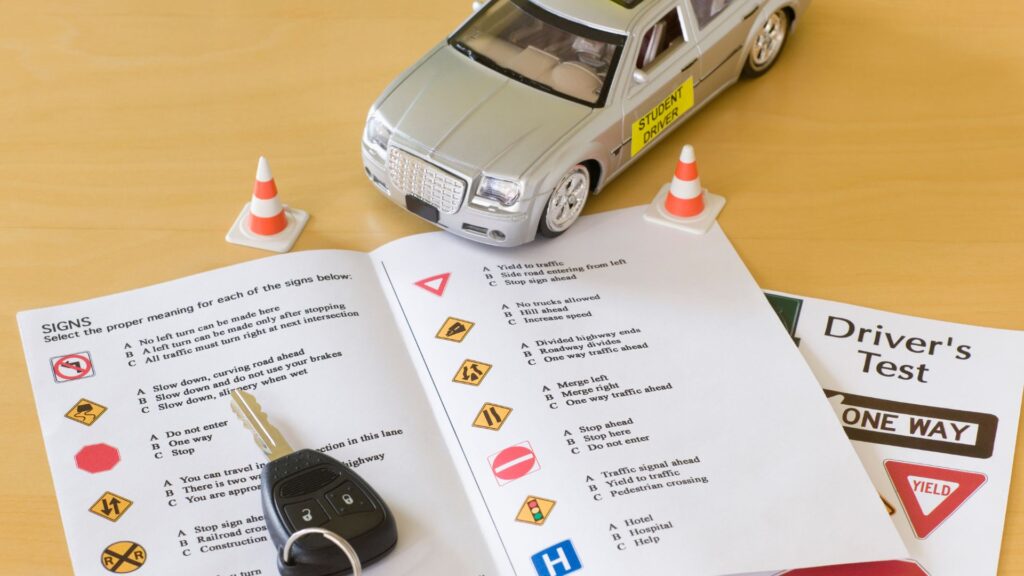 Drivers test study materials with toy car and traffic cones.