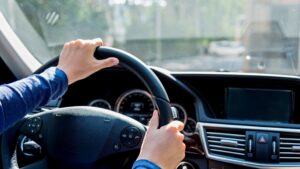 Person driving a modern car, hands on steering wheel.