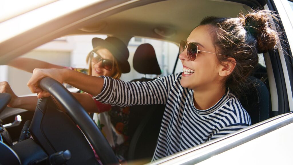 Happy women enjoying sunny car ride together.