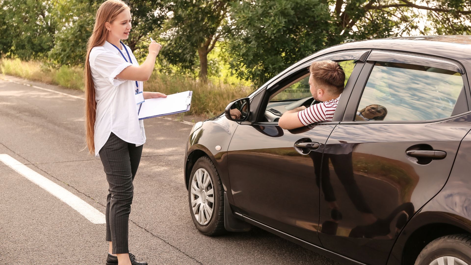 Woman with clipboard instructing driver on roadside.