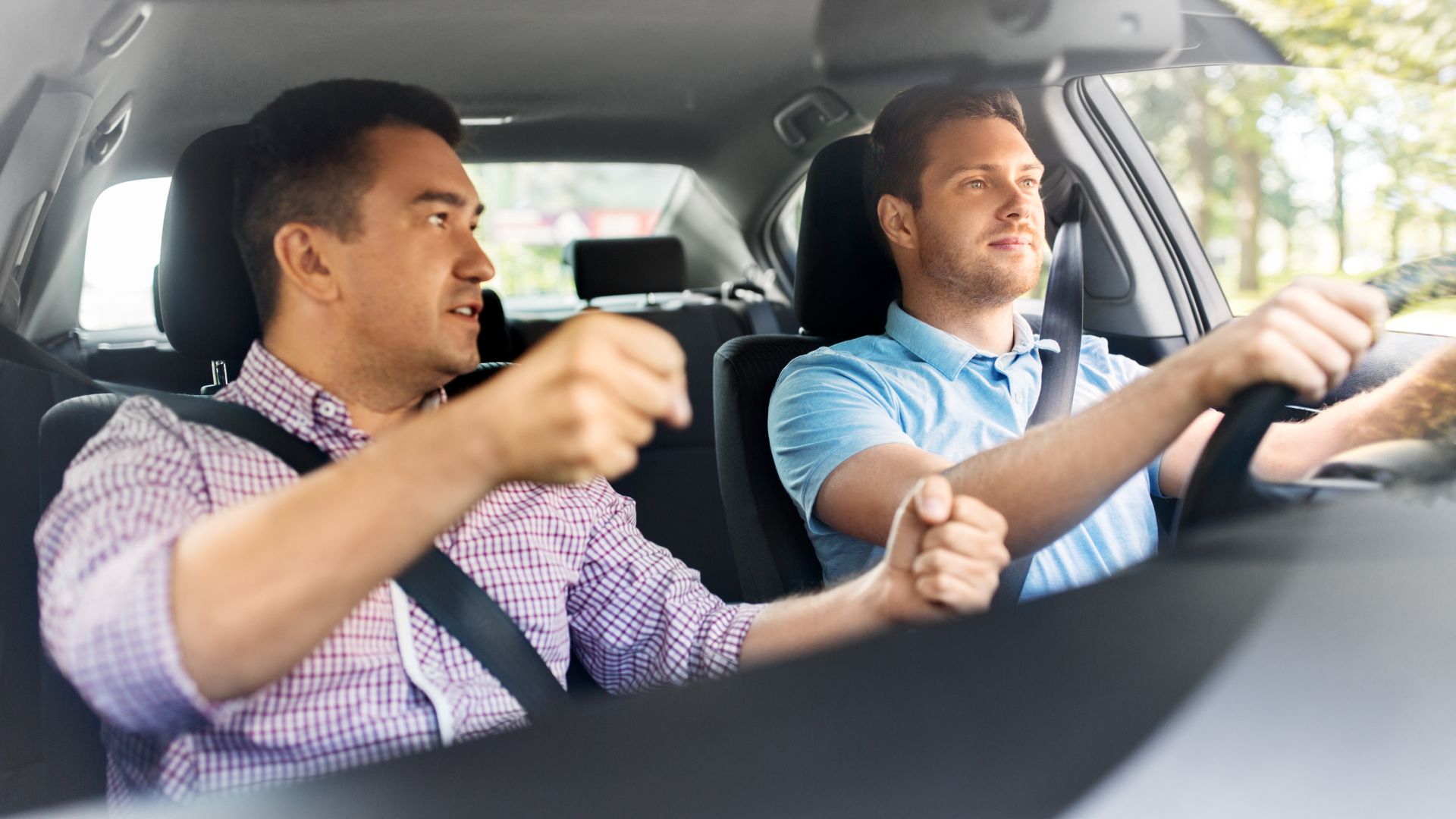 Two men driving and conversing in a car.